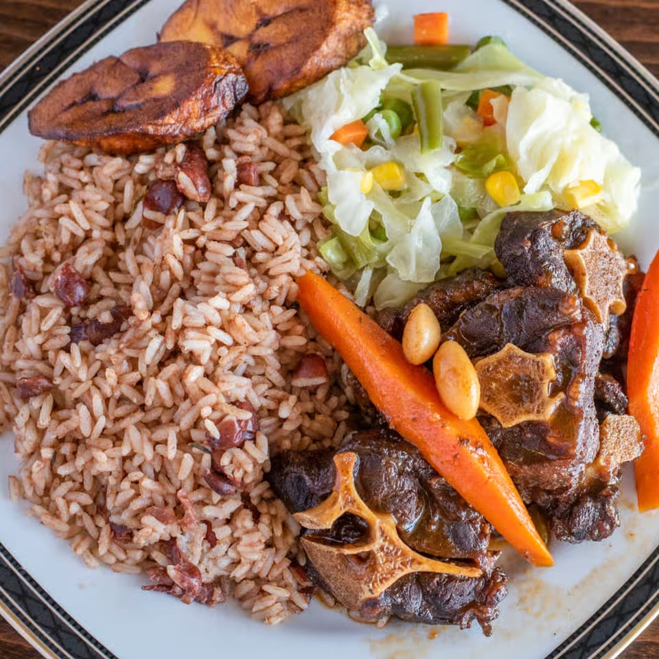 Curly's Caribbean oxtail with rice and peas, fried plantains, and steamed vegetables.